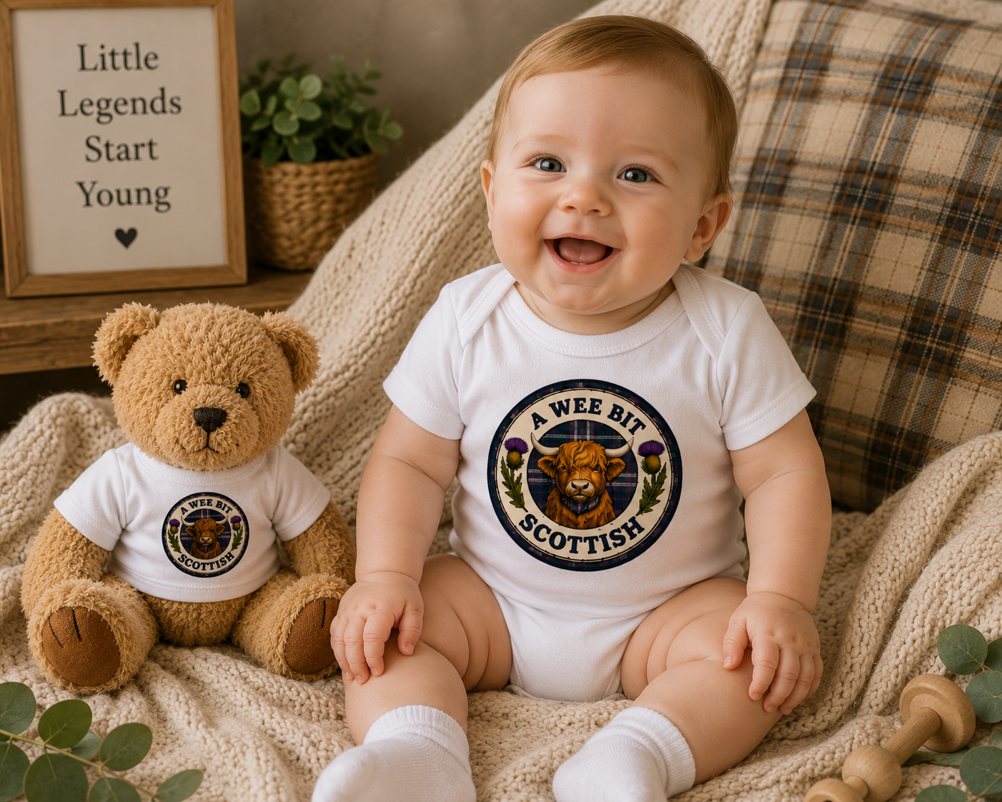 A Wee Bit Scottish baby bodysuit featuring a Highland Cow badge design with tartan detailing and Scottish thistles.