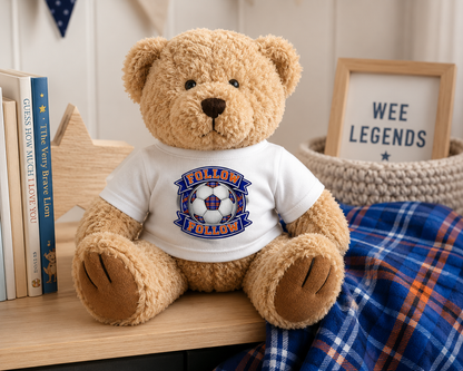 "FOLLOW FOLLOW teddy bear sitting on a nursery shelf wearing a white t-shirt featuring the FOLLOW FOLLOW football-inspired design."