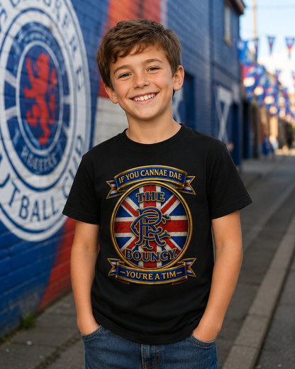 Smiling young boy wearing the If You Cannae Dae The Bouncy youth t-shirt in black featuring the exact Union Flag crest design and slogan, standing in a football-themed street setting.