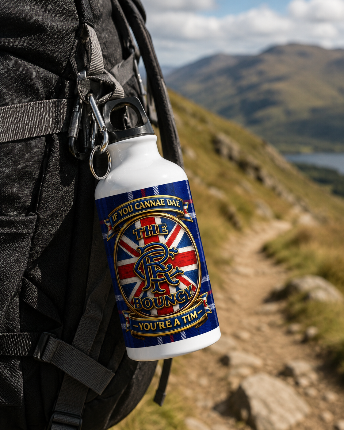 If You Cannae Dae The Bouncy aluminium sports water bottle clipped to a hiking backpack on a mountain trail with the tartan design clearly visible.