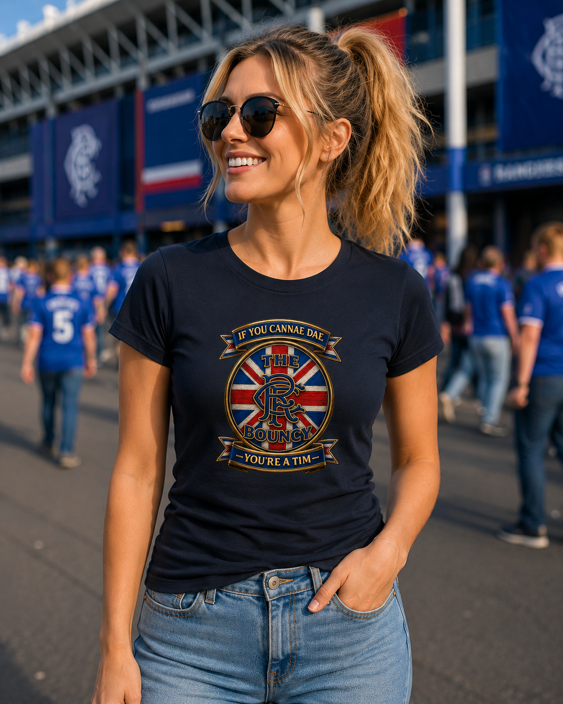 Woman wearing the If You Cannae Dae The Bouncy ladies fitted t-shirt in black featuring the exact Union Flag crest design, standing outdoors on a football match day.