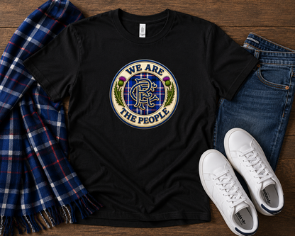 We Are The People Crest t-shirt displayed in a flat lay arrangement with jeans, white trainers and a blue tartan scarf.