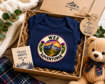 Wee Adventurer baby bodysuit presented in a gift box with teddy bear and Scottish-inspired packaging.