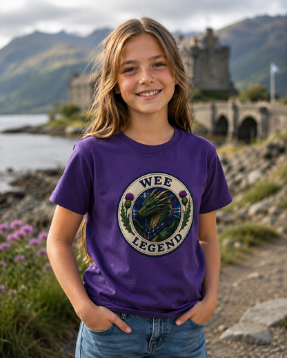 Child wearing the Wee Legend Dragon youth t-shirt outdoors in a Scottish-inspired countryside setting, featuring the detailed dragon crest artwork and tartan elements.