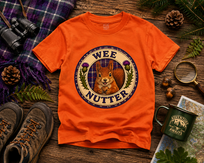 Folded Wee Nutter youth t-shirt displayed with woodland-inspired accessories and tartan details.