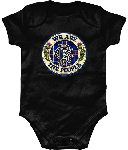 We Are The People badge baby bodysuit in black featuring tartan crest design with Scottish thistles and blue embroidered-style detailing.