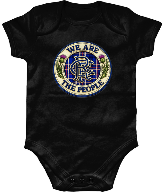 We Are The People badge baby bodysuit in black featuring tartan crest design with Scottish thistles and blue embroidered-style detailing.